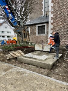 twee mannen , een met veiligheidshelm en vest en een andere werkman zijn de onderste stenen met behulp van een blauwe kraan aan het terugplaatsen.