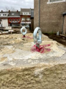 Project Oorlogsmonument Zonhoven, we zien een detail van ringen met een bout die door de gele steen van het moment geboord zijn.